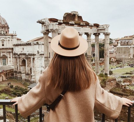 A woman in a hat and coat looking at the ruins.