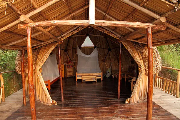 A geodesic dome made of wood, grasses, and thatch used as a room for guests.